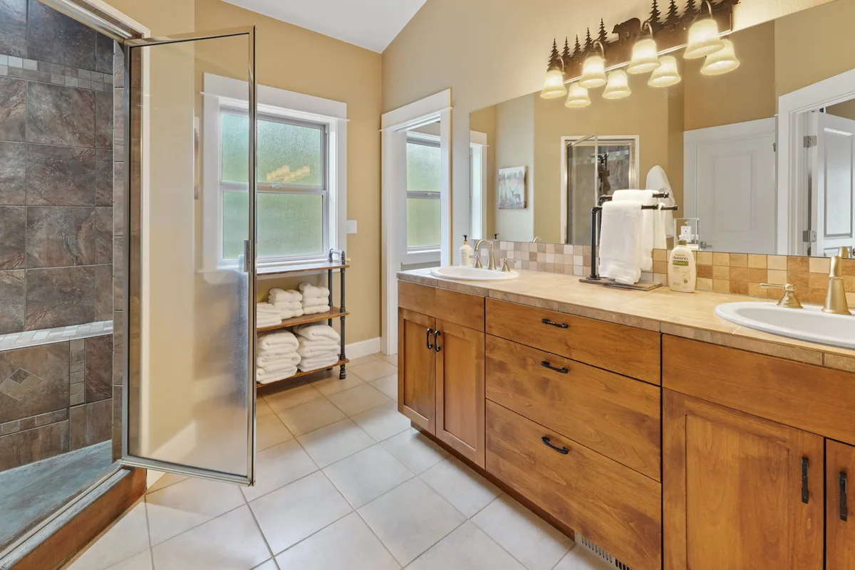 A spa-inspired bathroom with a spacious shower area, vanity with mirrors, and neatly arranged towels. The design is clean and inviting, echoing the promise of spa-like comfort and self-care rituals.