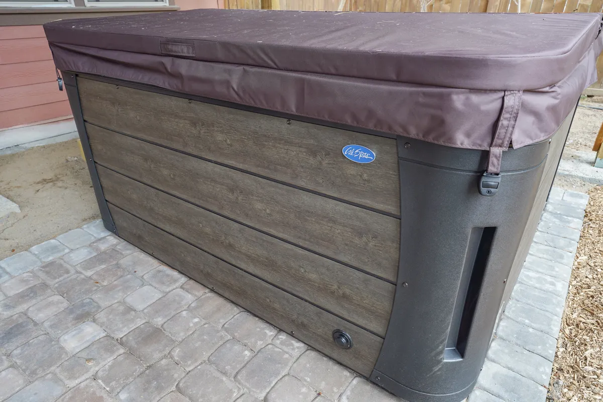 The image showcases a bubbling hot tub situated outdoors, surrounded by comfortable lounge seating and a scenic natural setting. The inviting lighting and visible stars above evoke a sense of relaxation and year-round enjoyment.